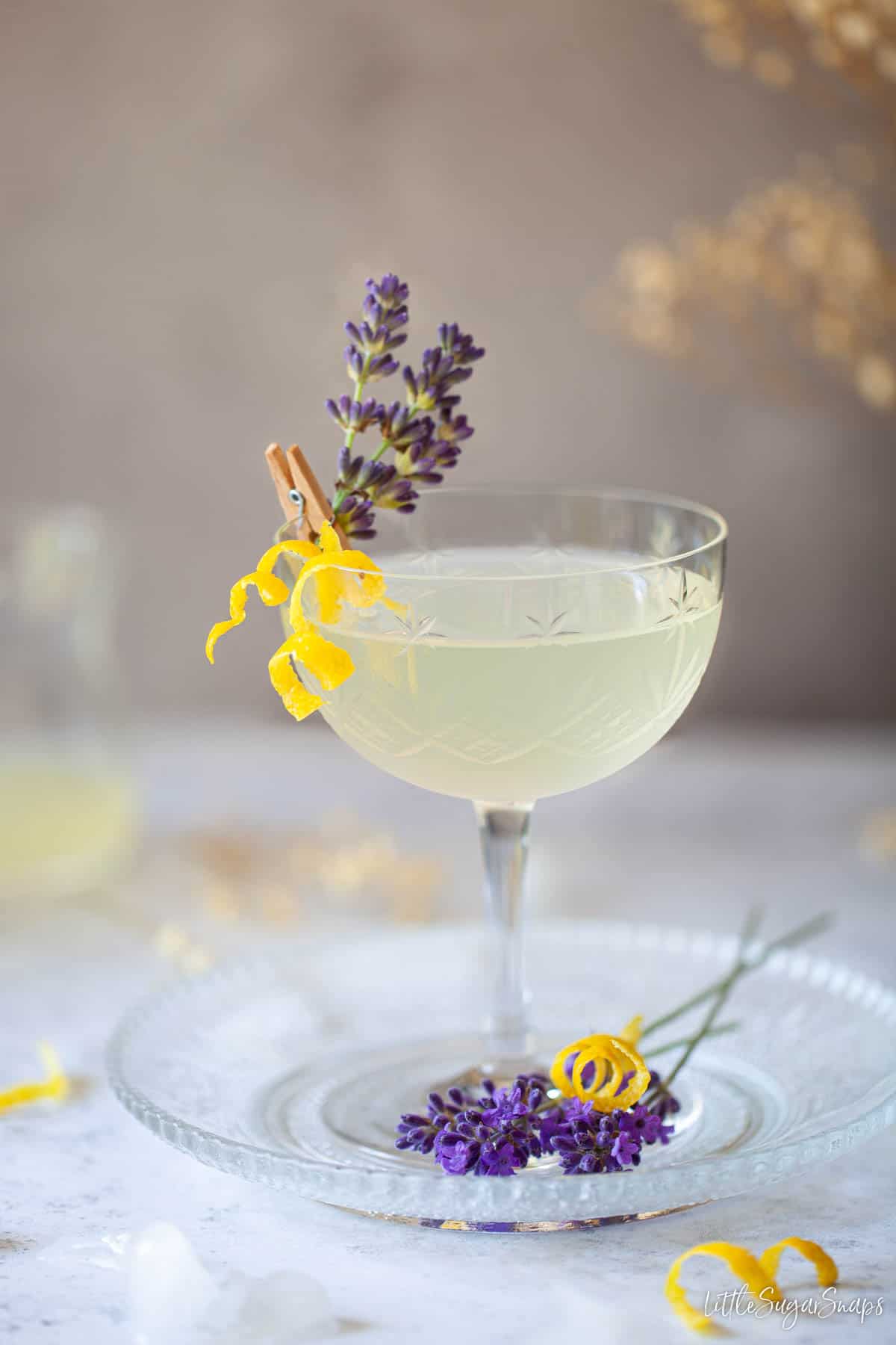 A limoncello cocktail garnished with lavender and lemon zest.