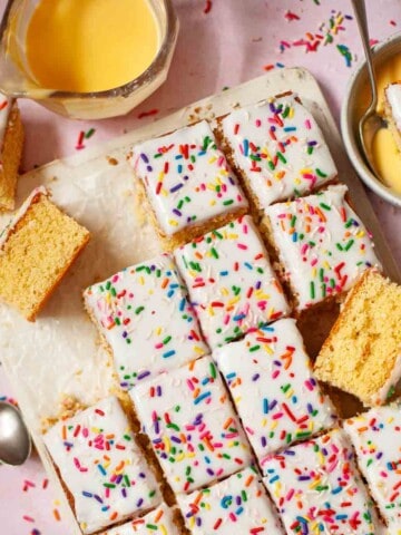 Chunks of old school sponge cake with icing, sprinkles and custard.