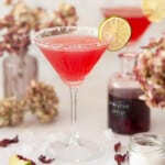 Close up of a hibiscus margarita cocktail in a salt rimmed glass with a dried lime wheel garnish.