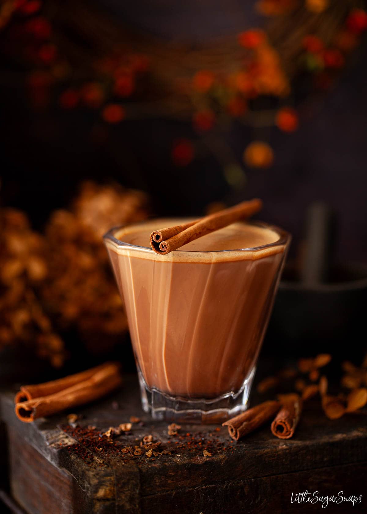 A glass of Aztec mocha topped with a cinnamon stick garnish in a cosy setting.