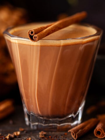 Close up of a Mexican mocha chocolate and coffee drink topped with a cinnamon stick.