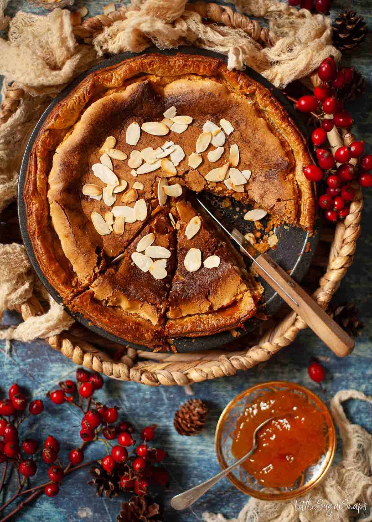 Bakewell pudding with a few slices cut from it. Toasted almond flkaes have been scattered on the top.