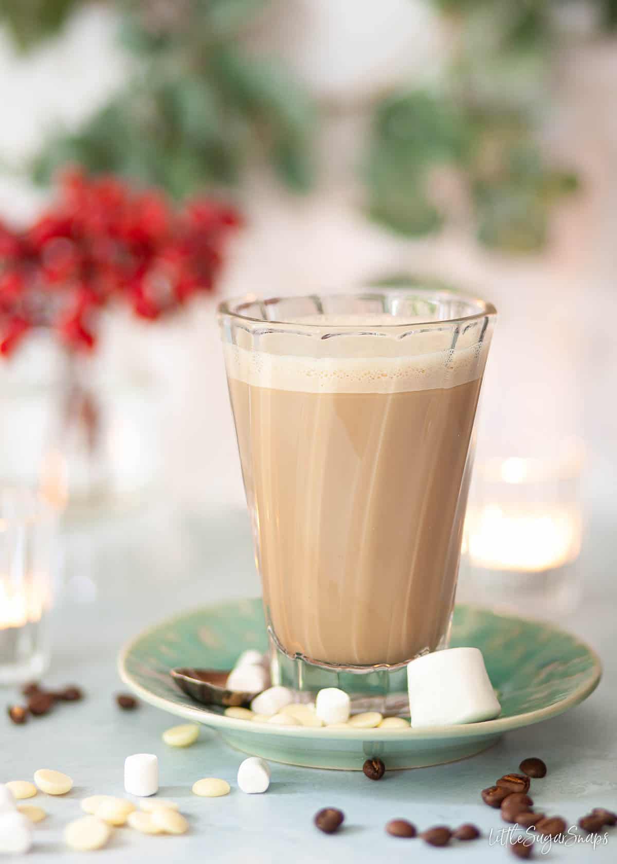 A peppermint coffee served in a tall coffee glass with marshmallows at theside.