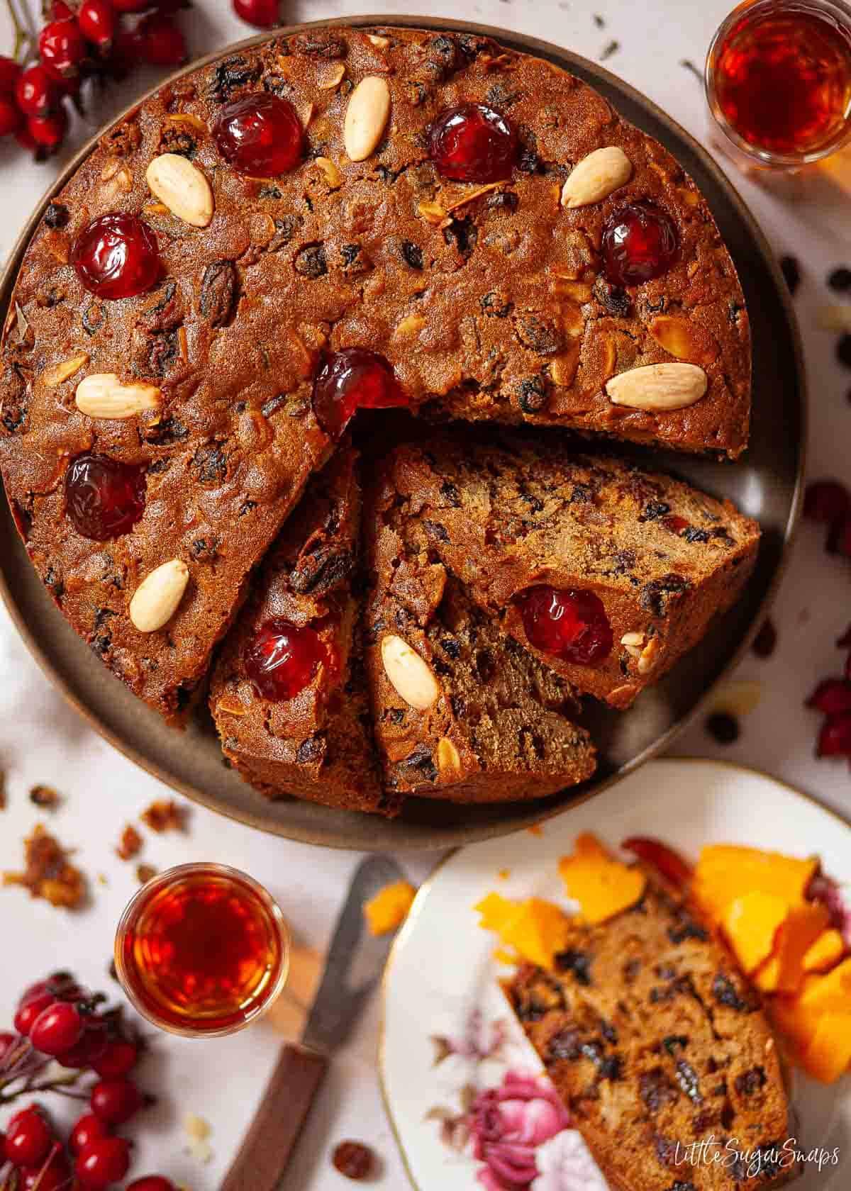 Sliced rum fruit cake with glacé cherries and almonds on the top.