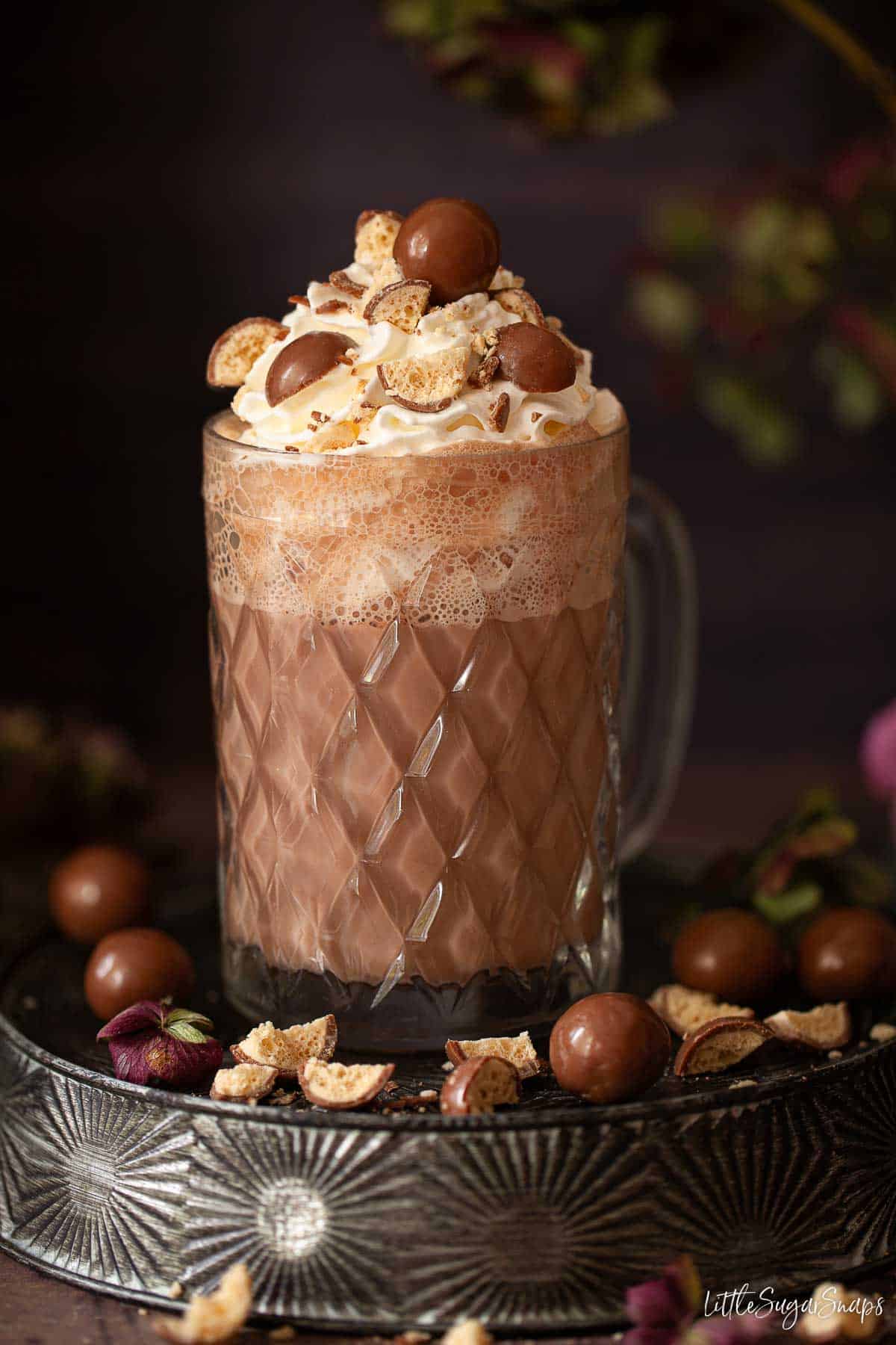 A malted chocolate drink in a vintage glass with cream and crushed chocolate on the top.