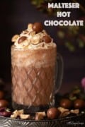 Labelled glass of Maltesers hot chocolate with whipped cream and crushed honeycomb chocolate garnish.