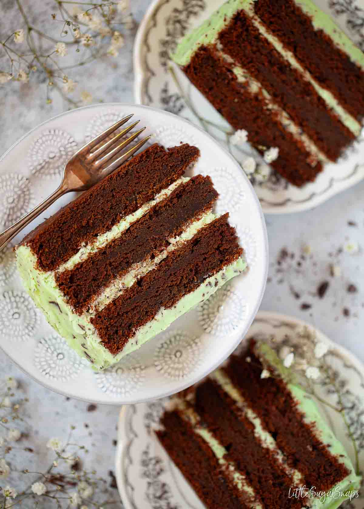 Three slices of chocolate mint cake on plates.