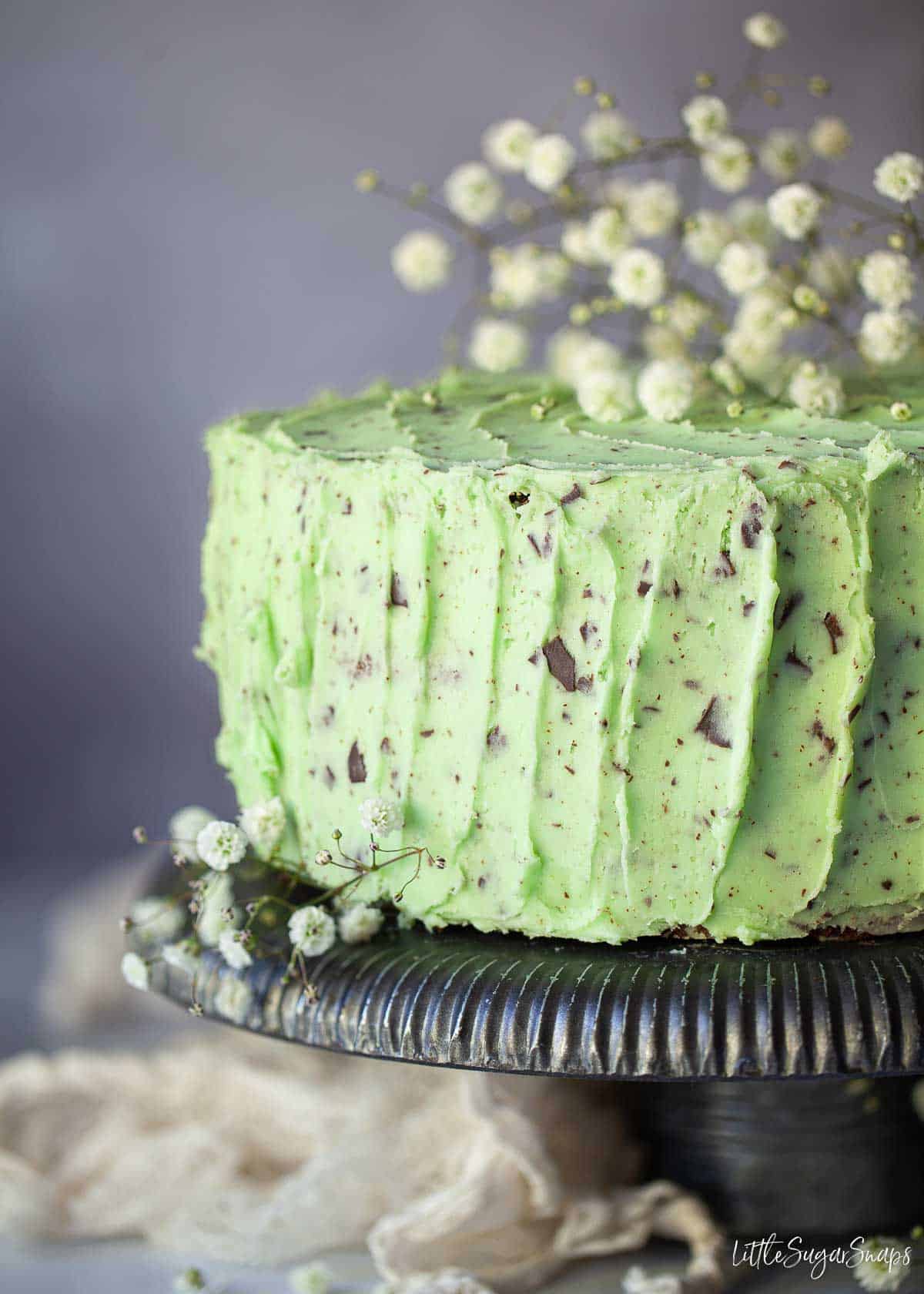 Close-up of a mint chocolate chip cake garnished with flowers.