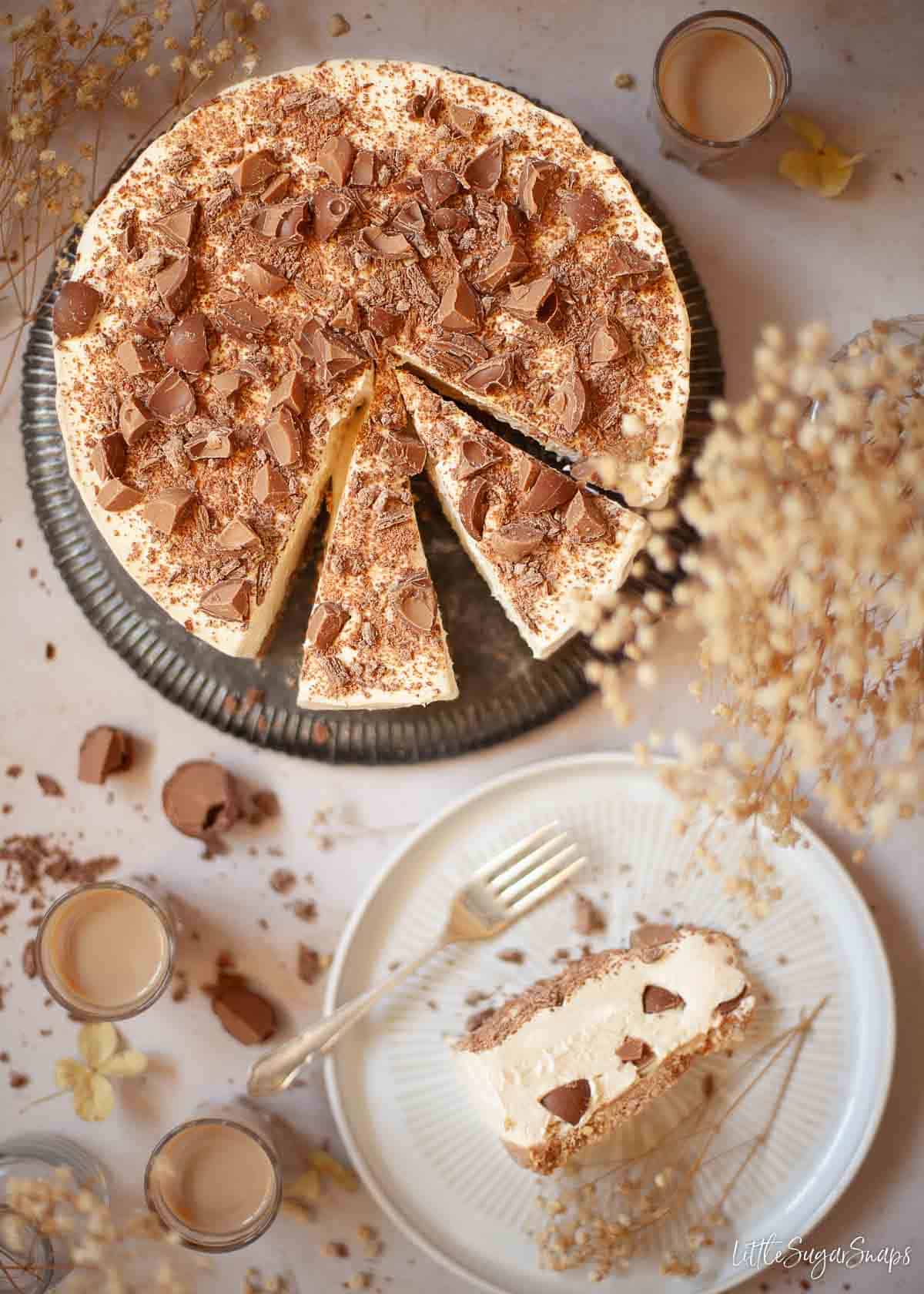 A part sliced no bake Baileys Irish cream cheesecake with one slice on a plate next to it.