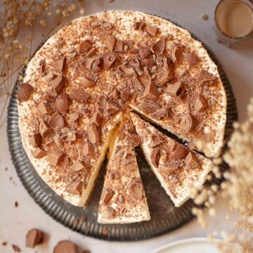 Overhead view of a part-sliced Irish cream cheesecake topped with chopped chocolates.