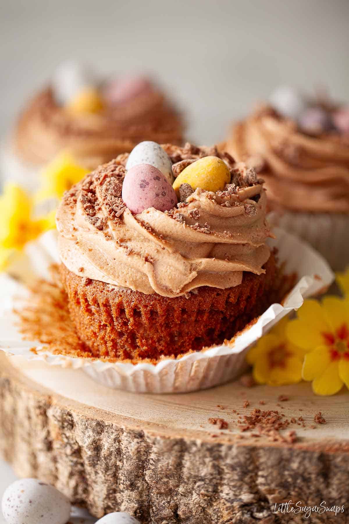 Easter themed chocolate cakes topped with Mini eggs and presented on a wooden board.