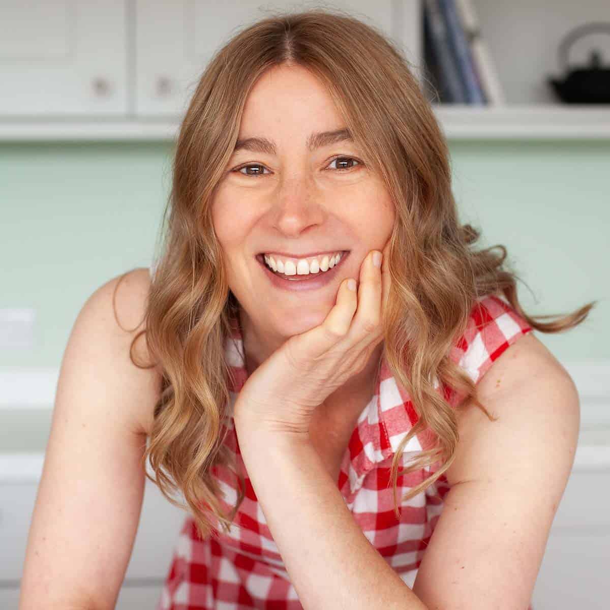 Jane Coupland (formerly Jane Saunders) smiling in red checked dress.