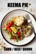 Lamb keema pie served on a plate with salad. With text overlay.