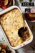 Potato topped minced lamb pie with a portion served from it and text overlay.