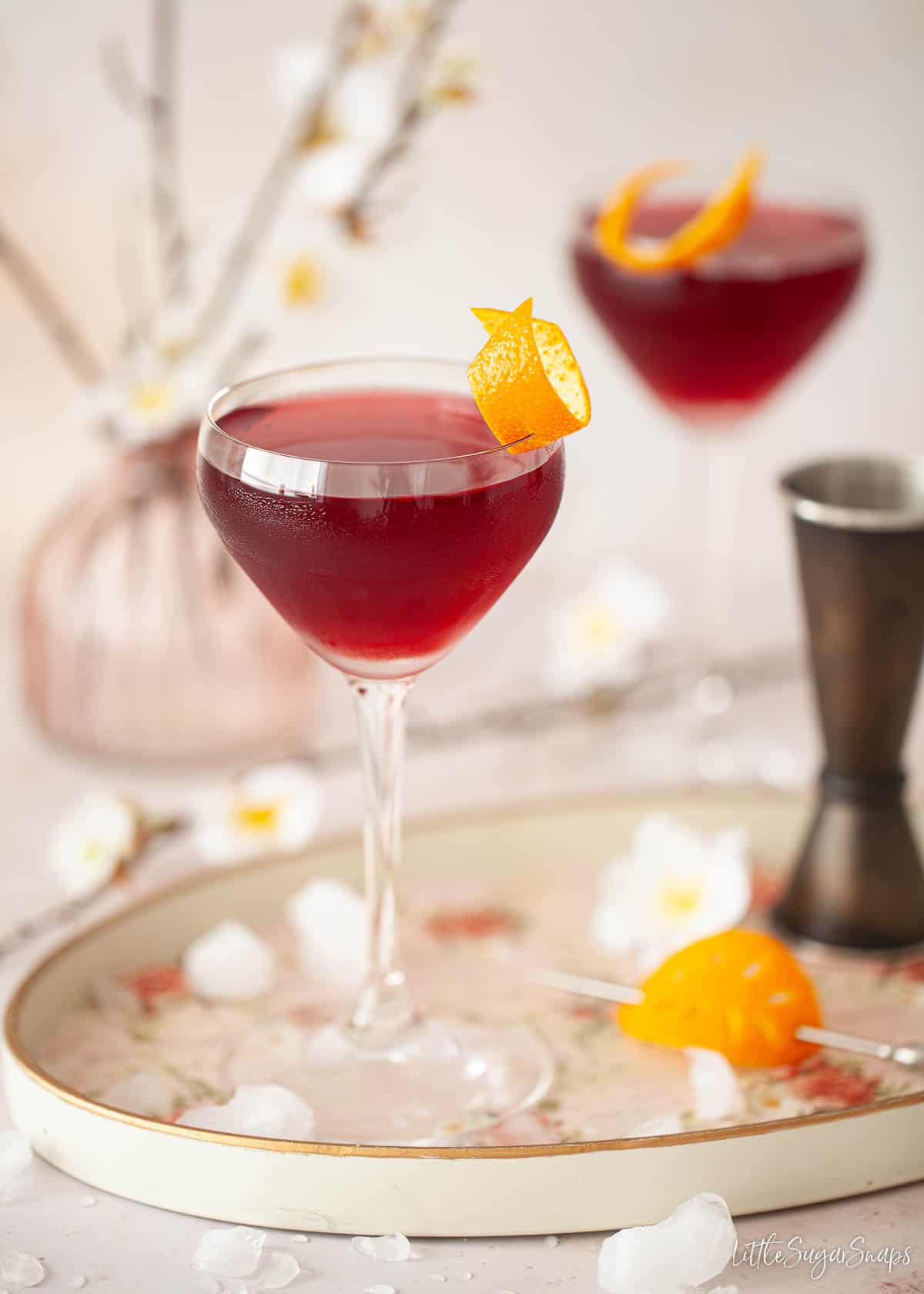 Two creme de cassis cocktails in Nick & Nora glasses garnished with orange zest.