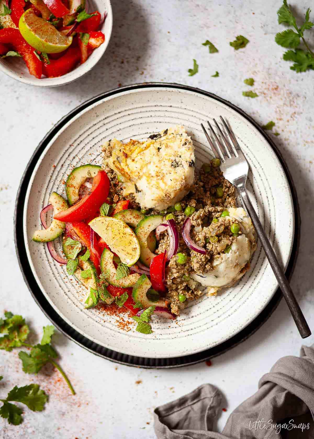 A portion of lamb keema pie on a plate with a side salad.