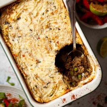 Close up of a large potato-topped minced lamb pie with a portion removed from it.