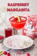 Raspberry margarita in a glass rimmed with crushed fruit and garnished with fruit.