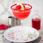 A raspberry margarita cocktail with crushed raspberry rim and fruit skewer garnish.