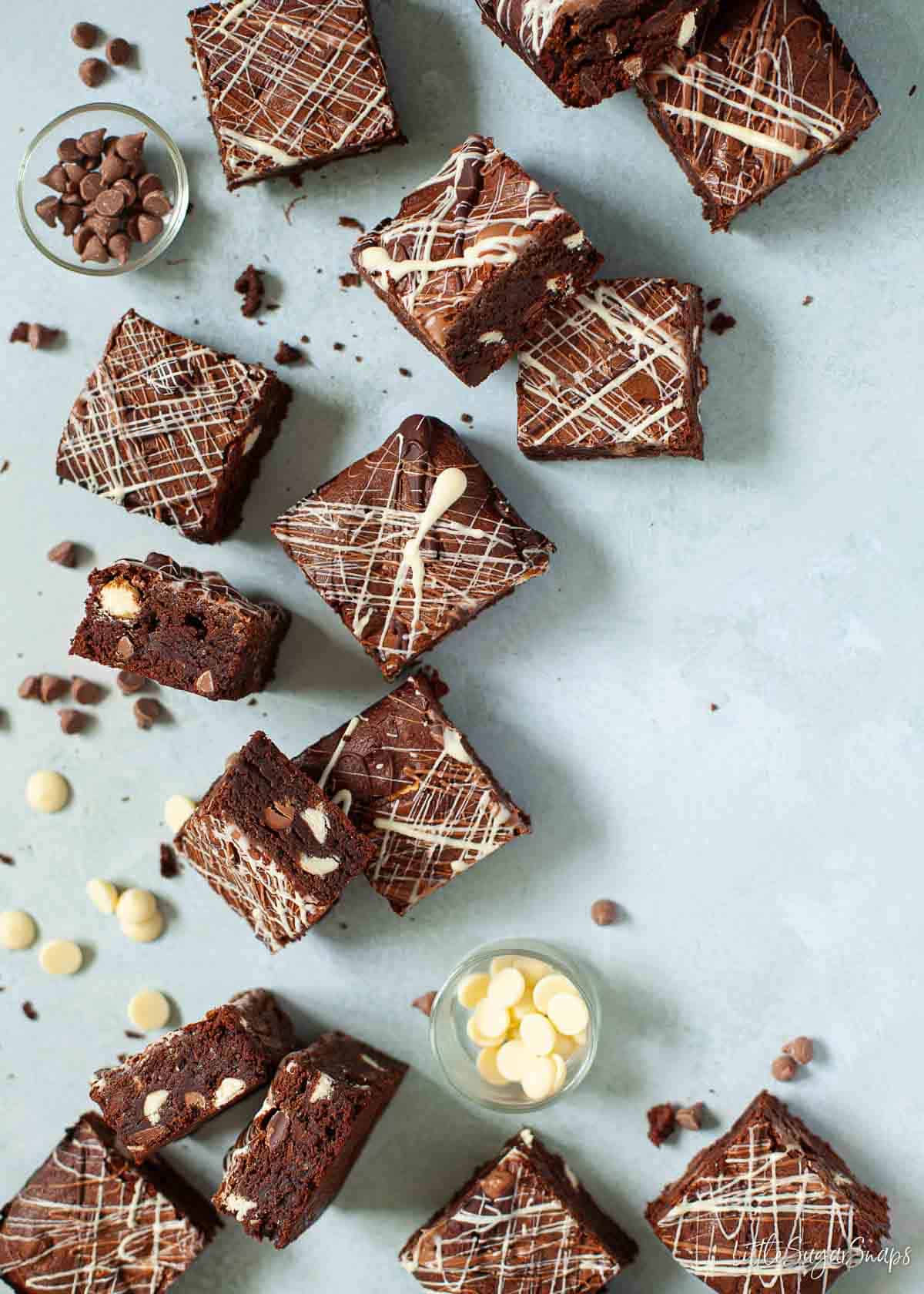 Squares of milk, dark and white chocolate brownies on a worktop with chocolate chips.