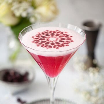 Close up of a blueberry gin cocktail with a stencil fruit garnish on top.