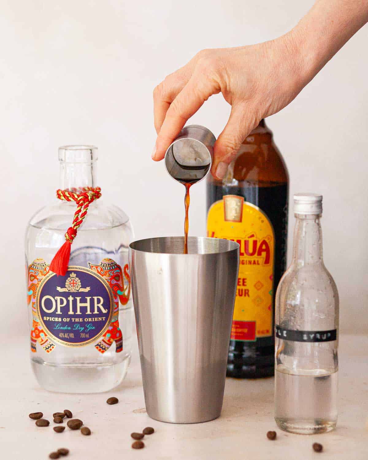 Coffee liqueur being poured into the base of a cocktail shaker.