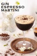 A gin espresso martini garnished with coffee beans and ground coffee. With text overlay.