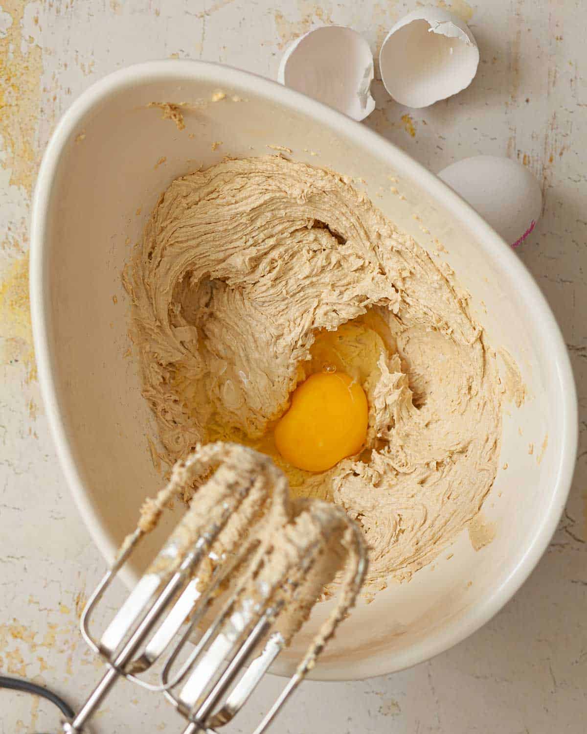 Egg in a bowl of cake batter ready to be mixed in.