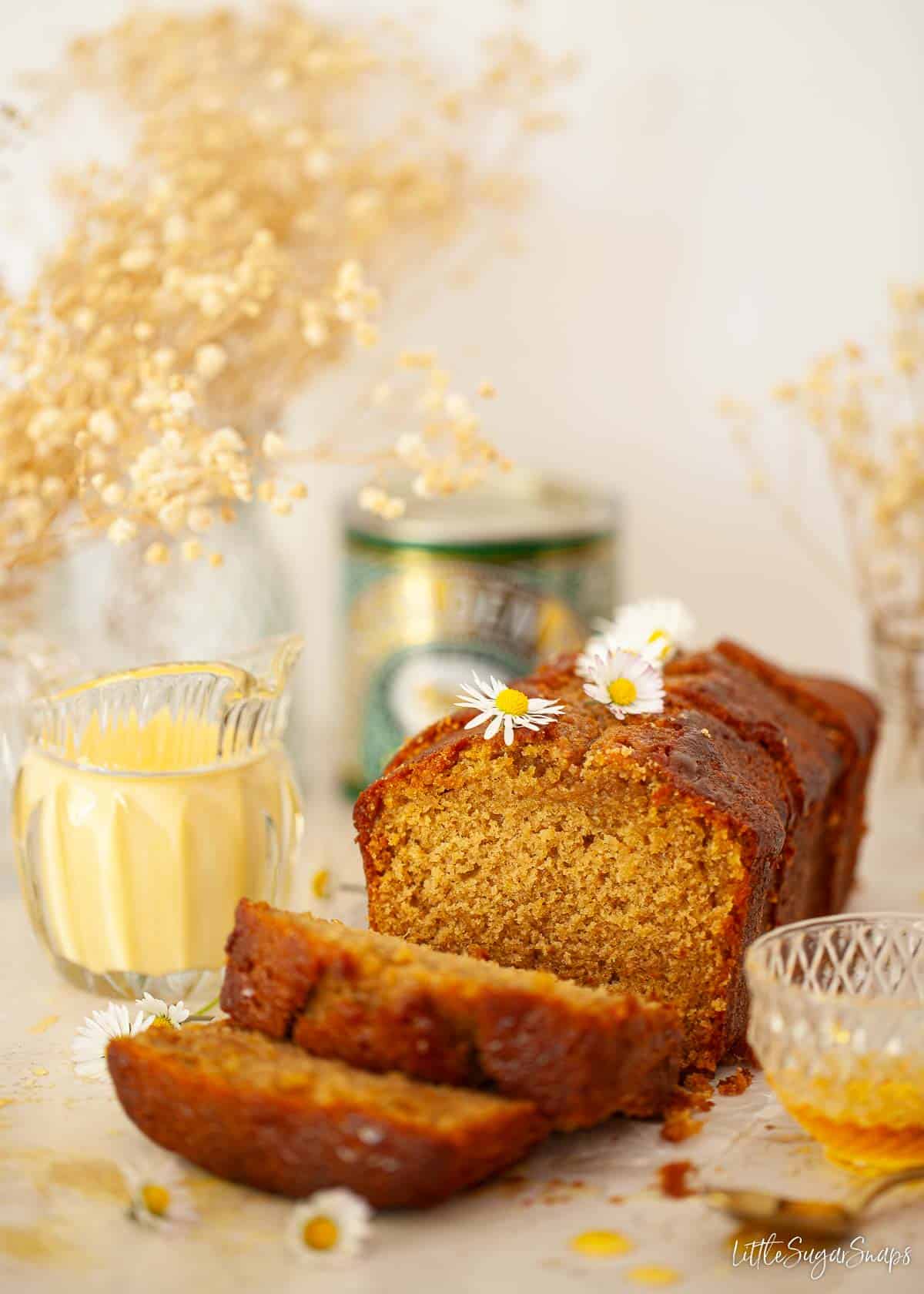 Golden syrup cake with a tin of syrup and a jug of custard.