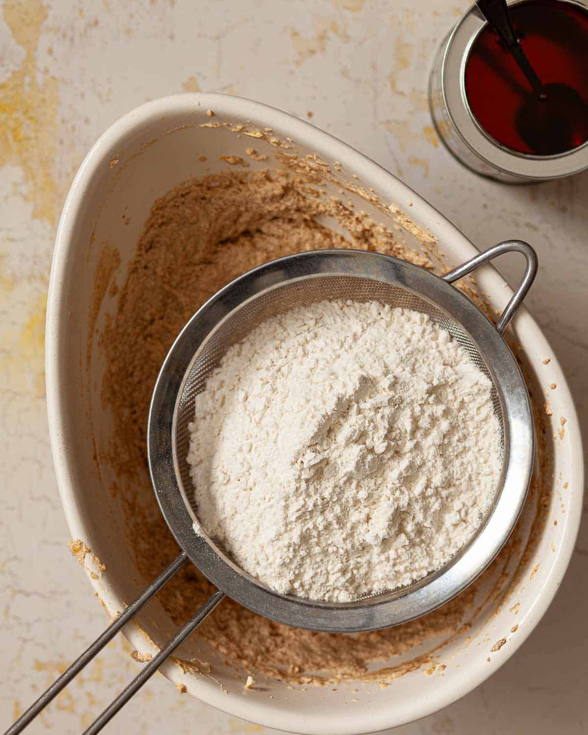 Flour in a sieve suspended over a mixing bowl.