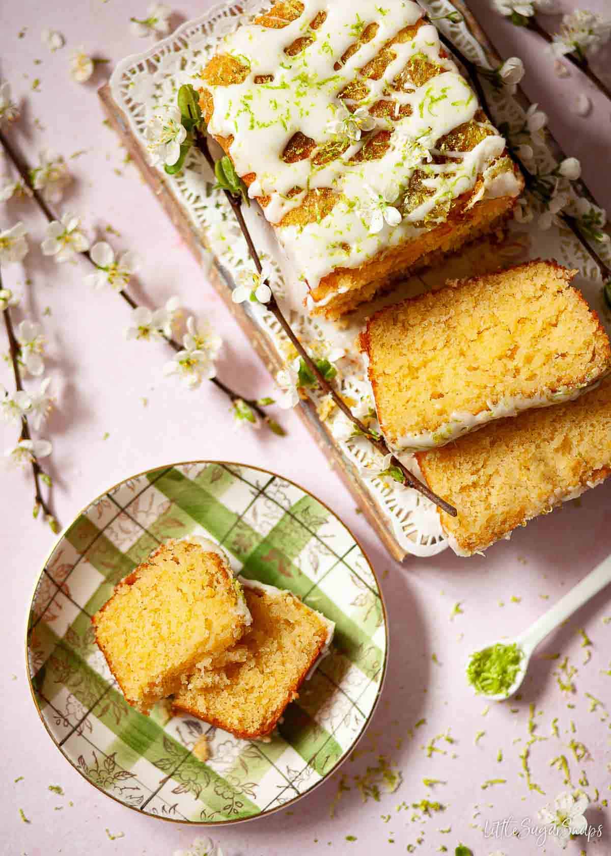 Overhead view of a lime loaf cake with a slice on a plate.