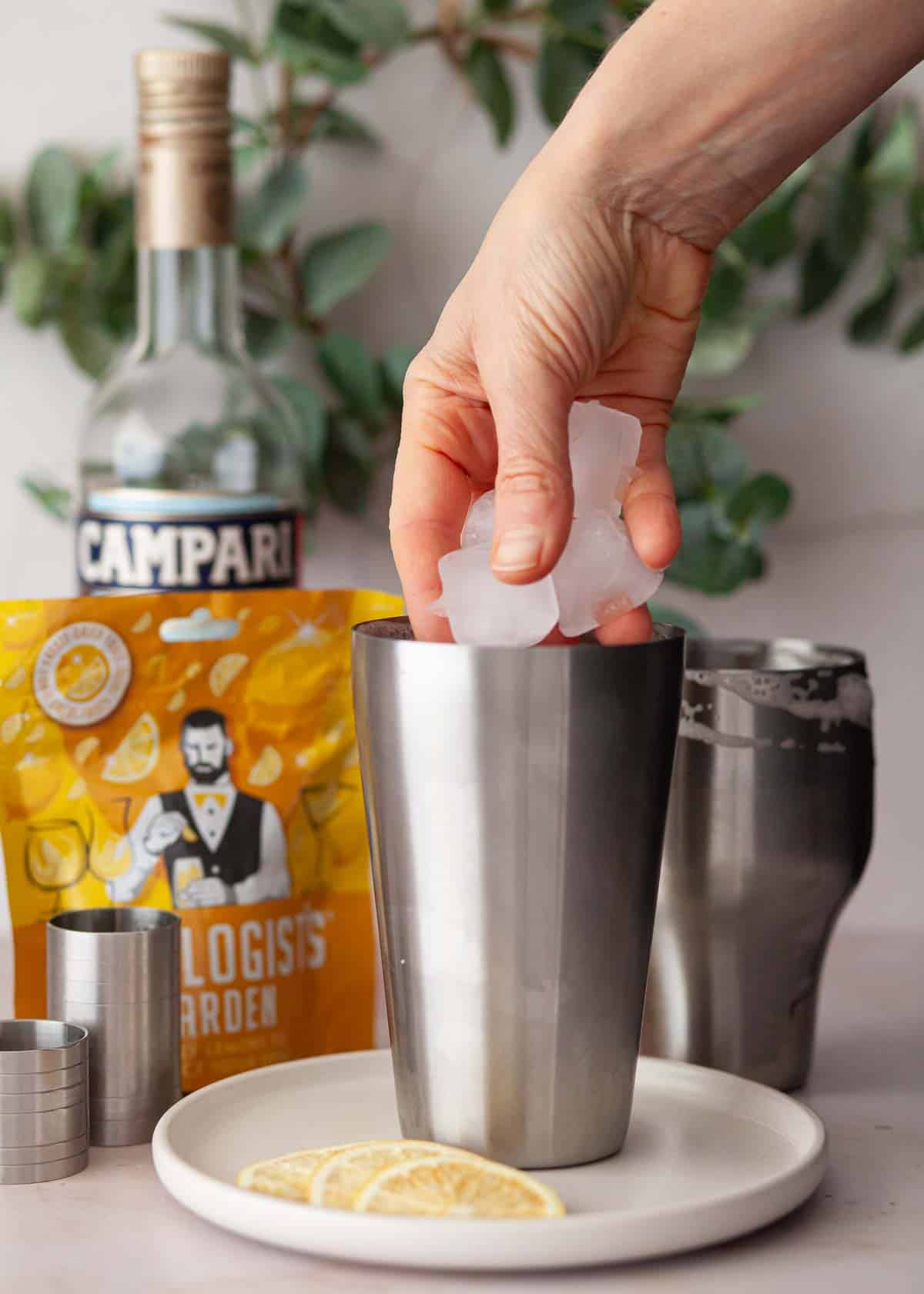 Ice being placed inside of a cocktail shaker.