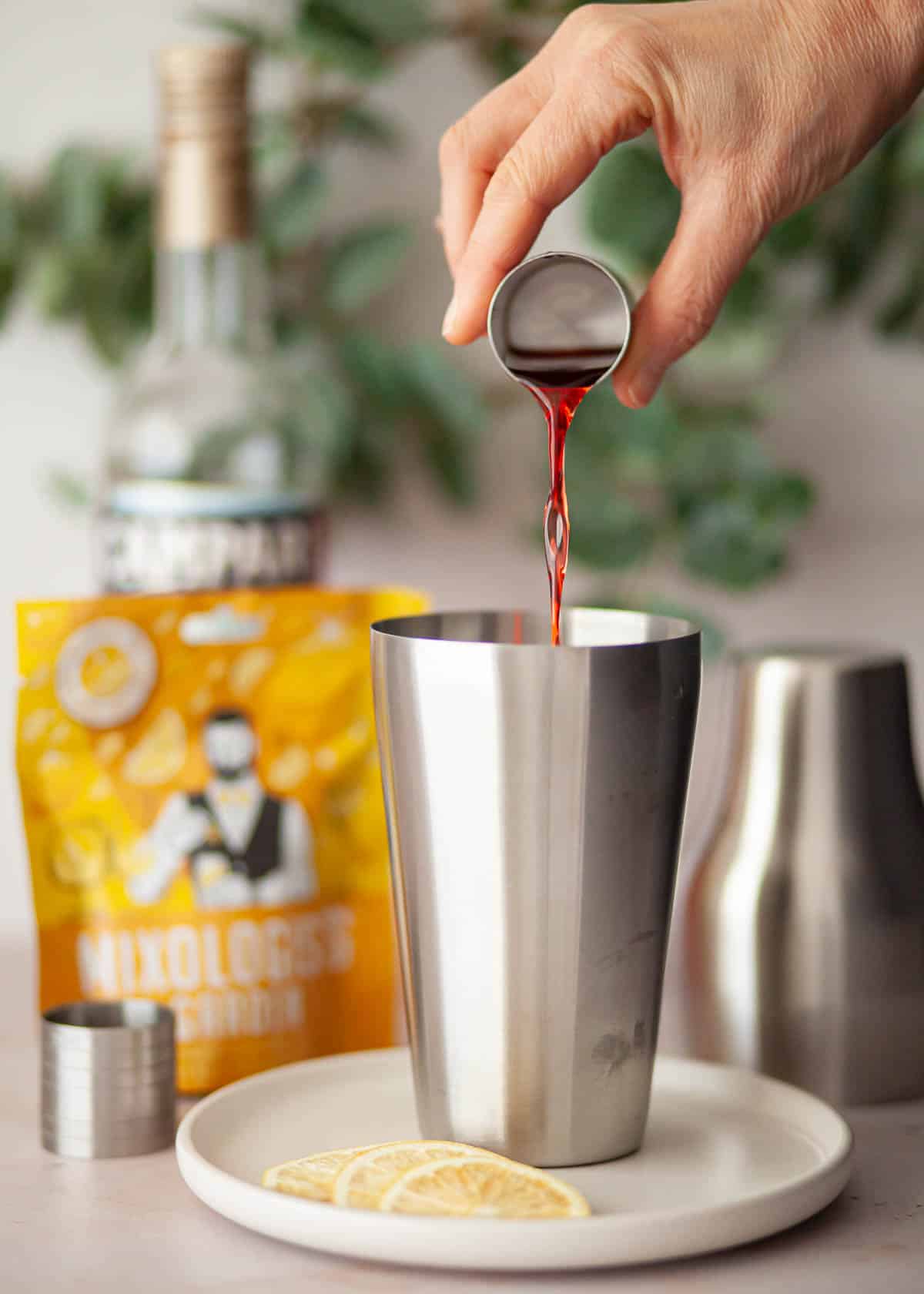 Alcohol being poured into a cocktail shaker.