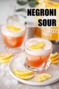 Two glasses of Negroni sour with egg white foam and lemon slice garnish. With text overlay.