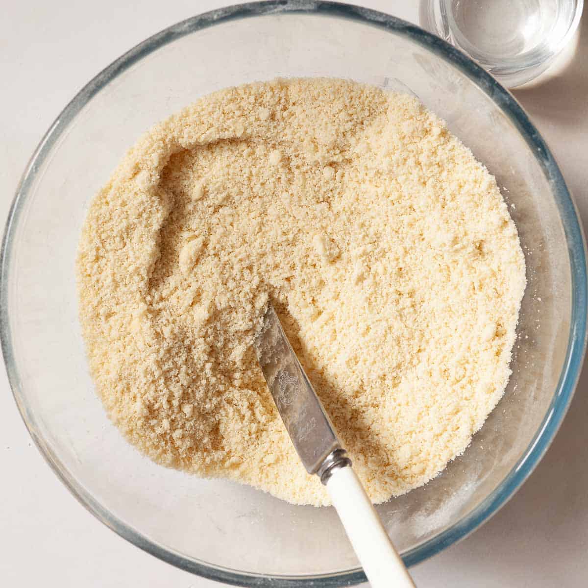 A bowl containing butter rubbed into flour.