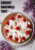 A cherry and almond tart topped with glacé icing and red glacé cherries with text overlay.