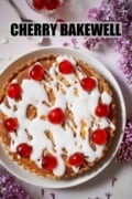 A cherry Bakewell tart topped with glacé icing and red glacé cherries with text overlay.