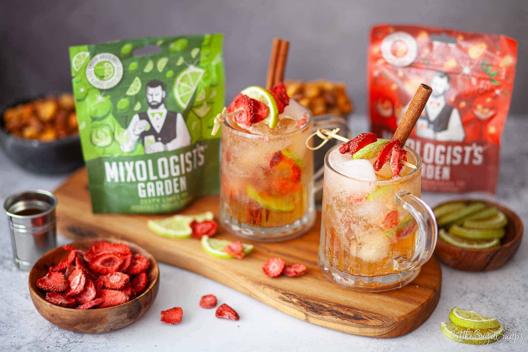 Two glasses of Southern cider cocktail garnished with freeze-dried fruit on bamboo picks.