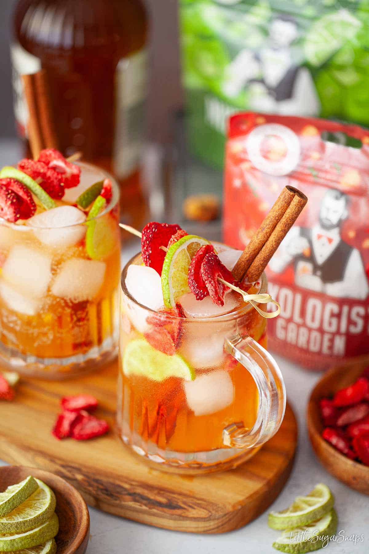 Southern cider cocktails in tankards garnished with cinnamon and freeze-dried fruit on skewers.