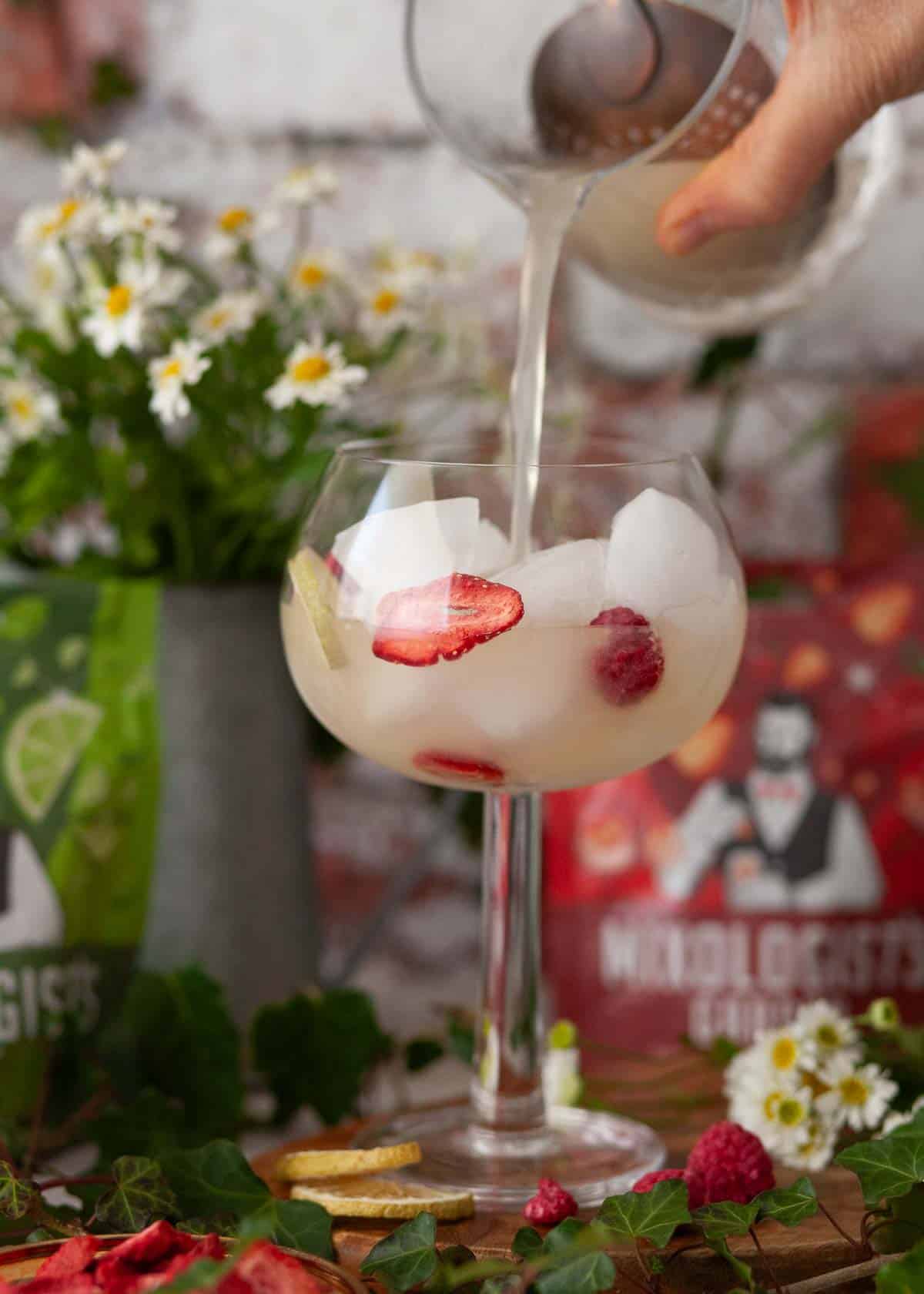 A person pouring an alcoholic drink into a glass.