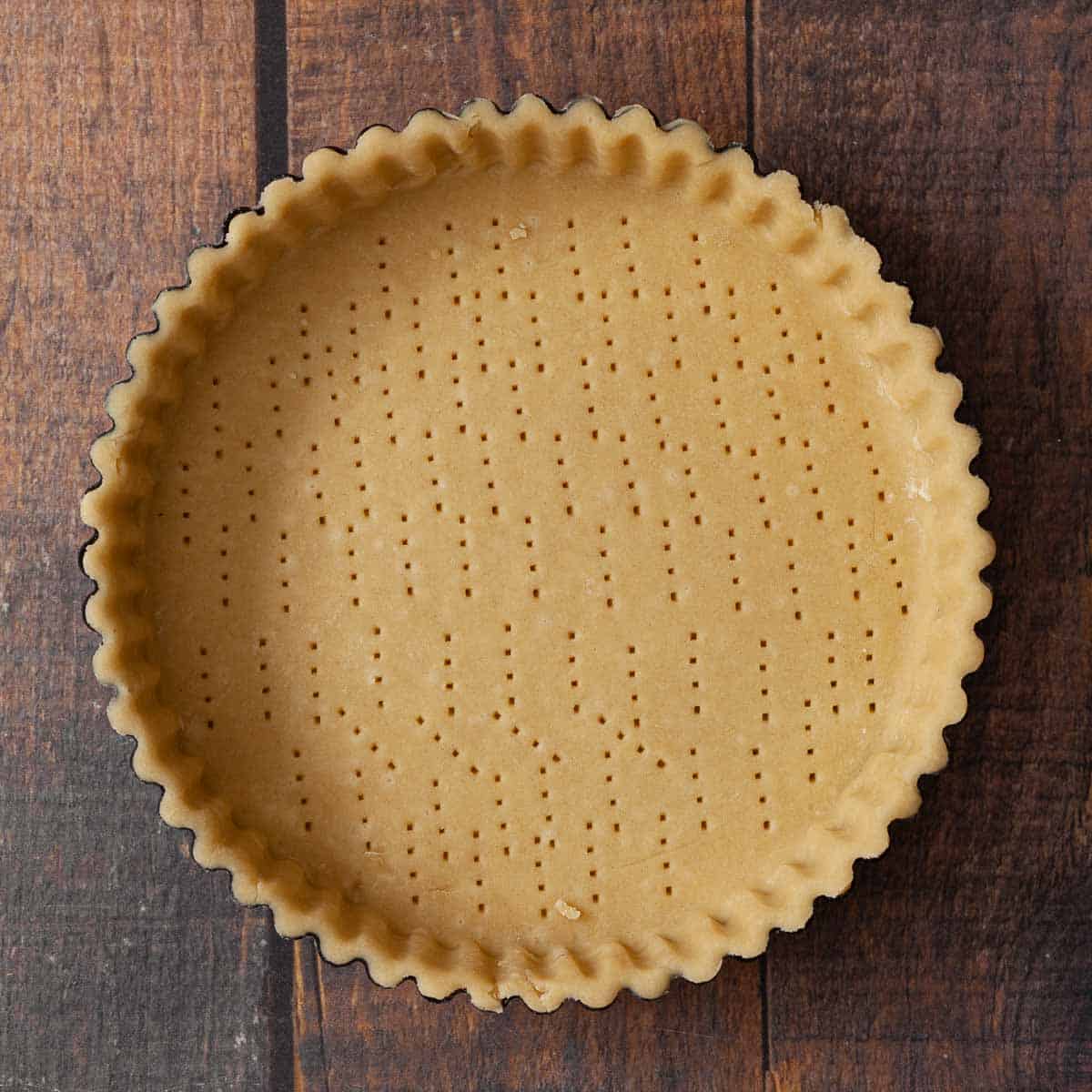 Shortcrust pastry in a tart case with the base pricked ready for baking.