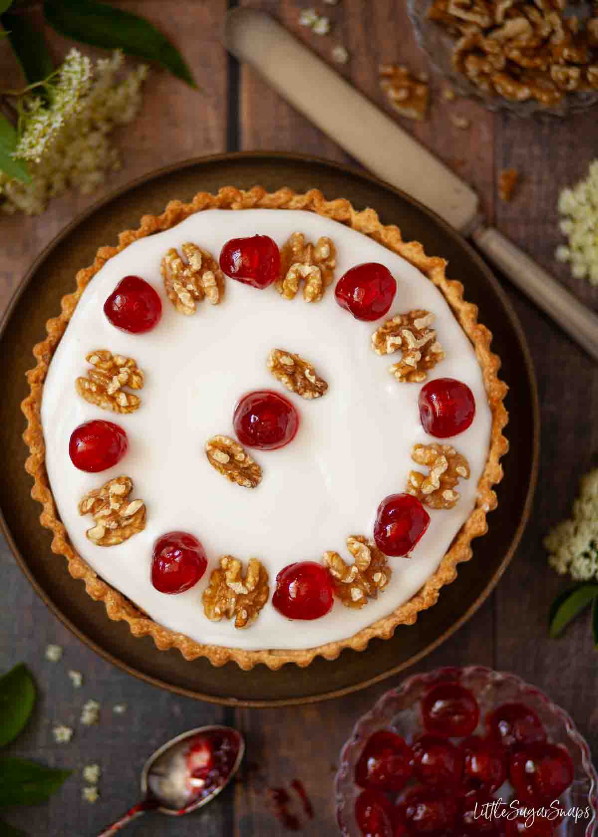 A whole jam sponge cake tart with icing, cherries and walnuts