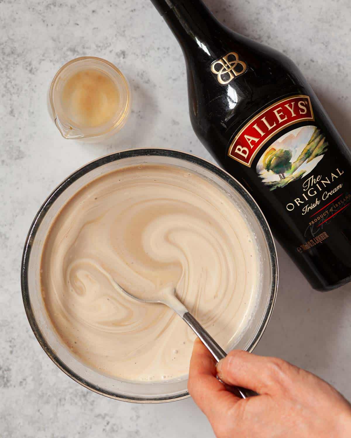 Person stirring Baileys into the base for an ice cream with alcohol.