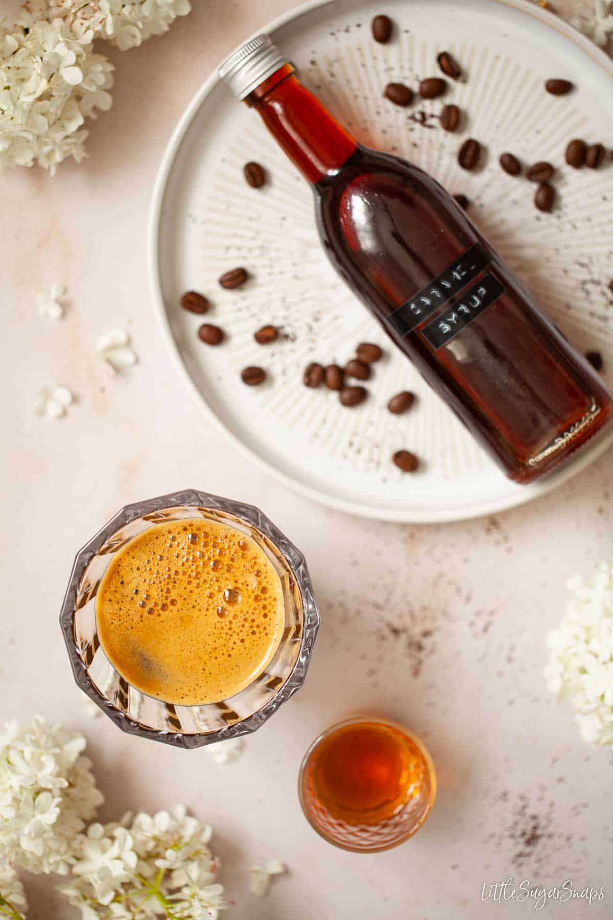 Homemade caramel syrup for coffee in a bottle with a shot of espresso coffee alongside.