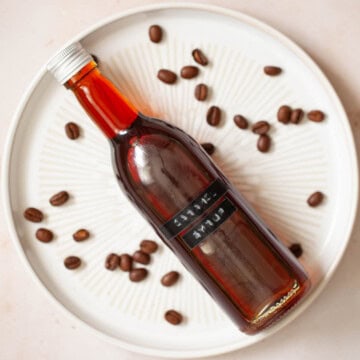 Close up of a bottle of homemade caramel syrup for coffee on a plate.
