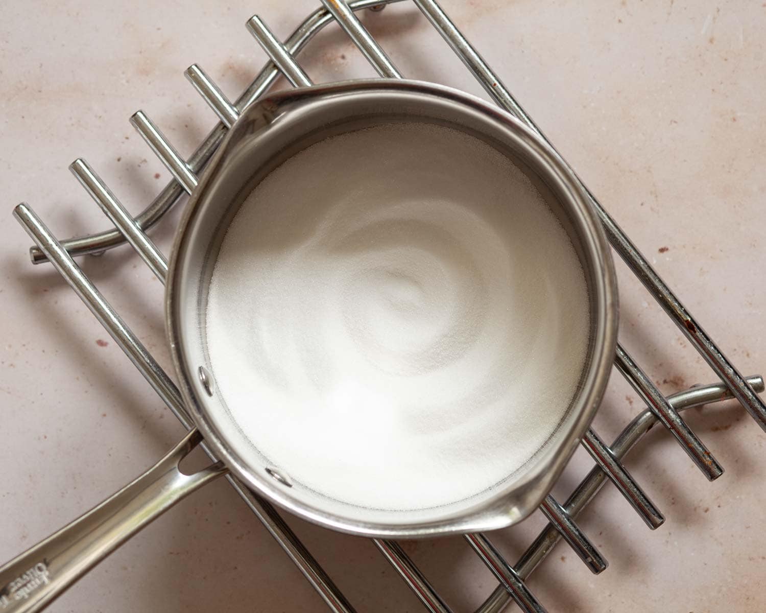 Sugar in a saucepan on a wire rack.