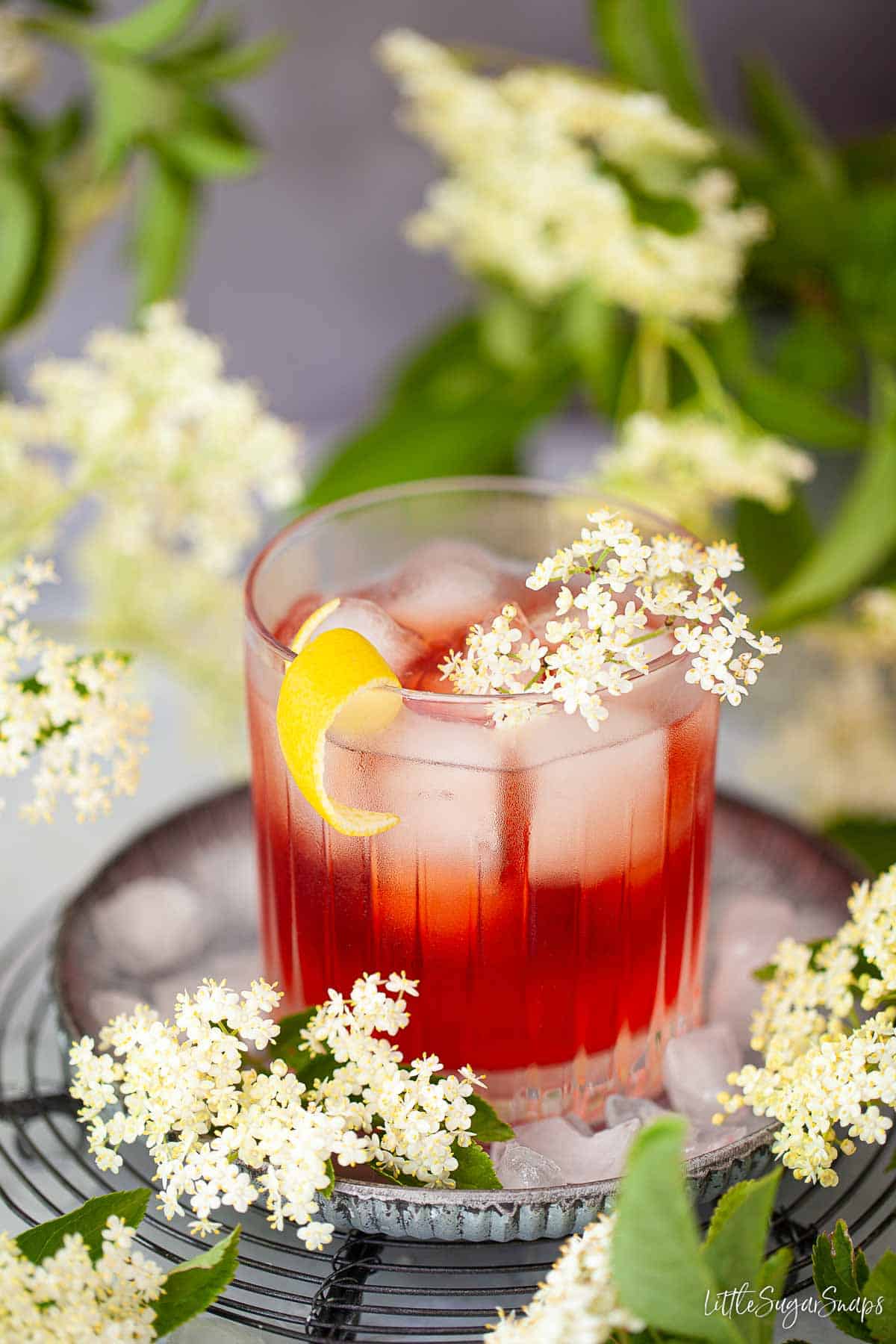 A negroni variation made elderflower liqueur and gin and garnished with lemon and elderflowers.