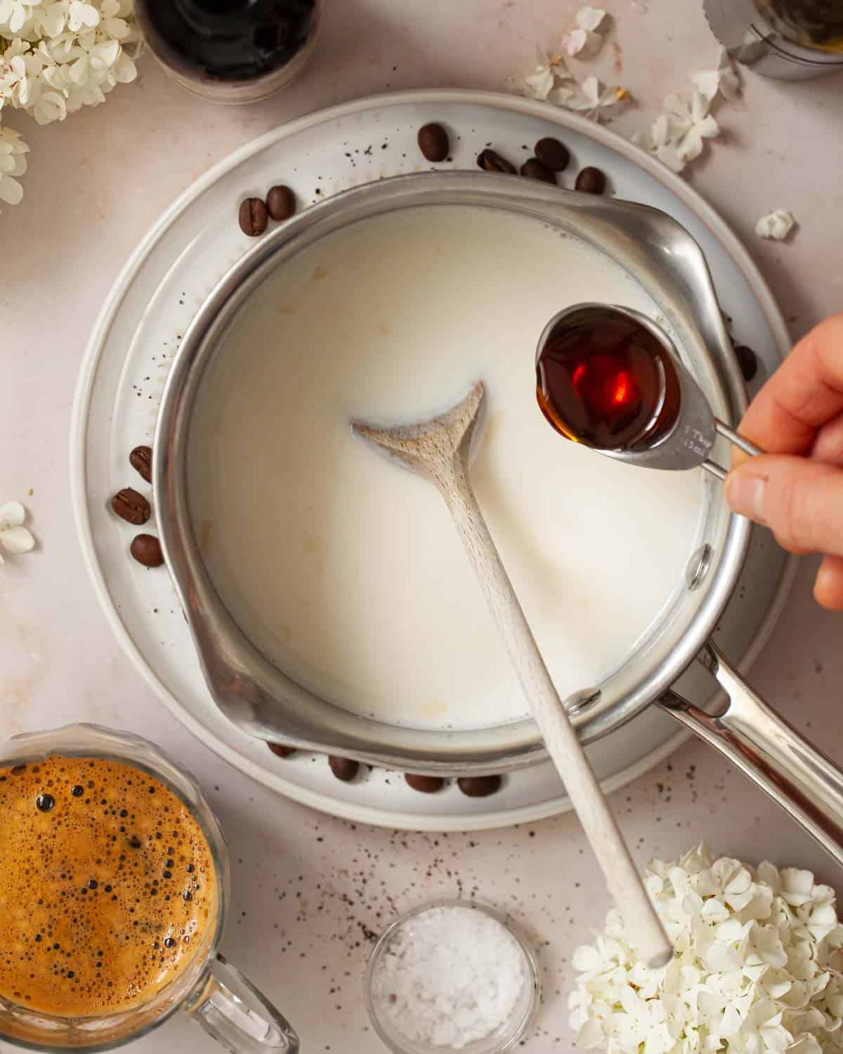 Caramel syrup being added to a pan of milk.