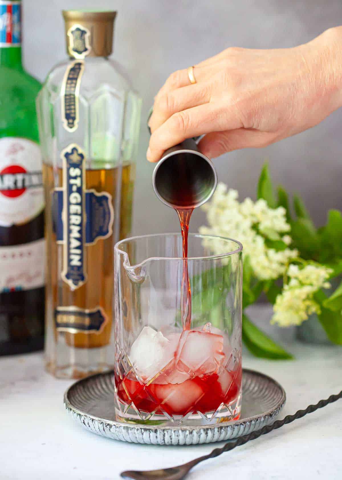 Campari being poured into a cocktail mixing jug with ice.