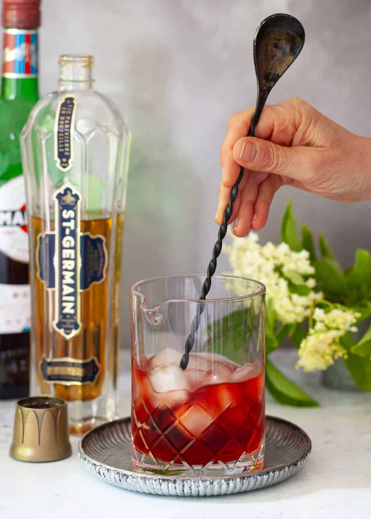 A Camapri and St Germain gin cocktail being stirred with ice.